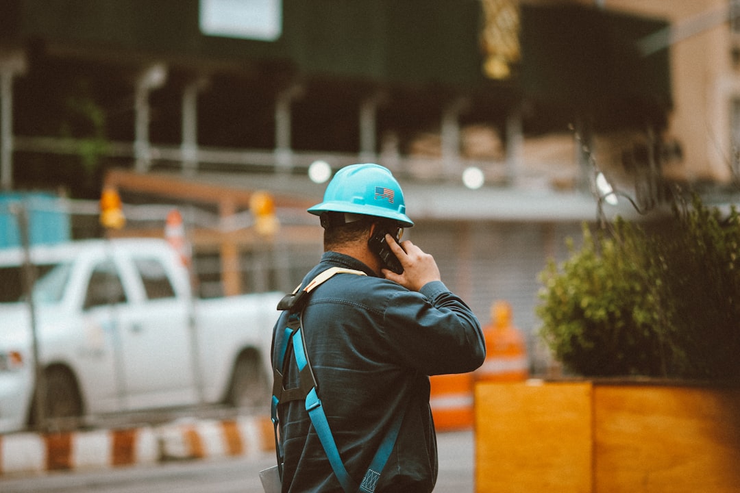 Contractor in blue jacket and orange hard hat on a job site